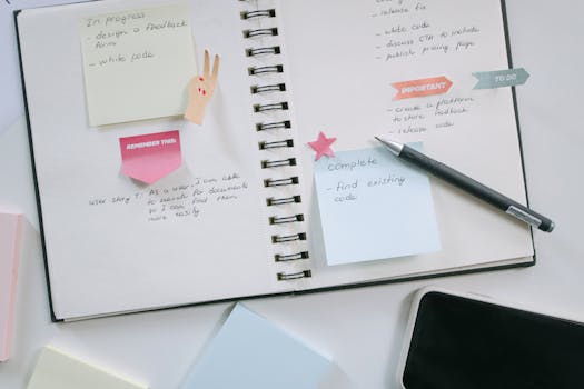 High-Angle Shot of a Notebook and a Pen Beside a Mobile Phone